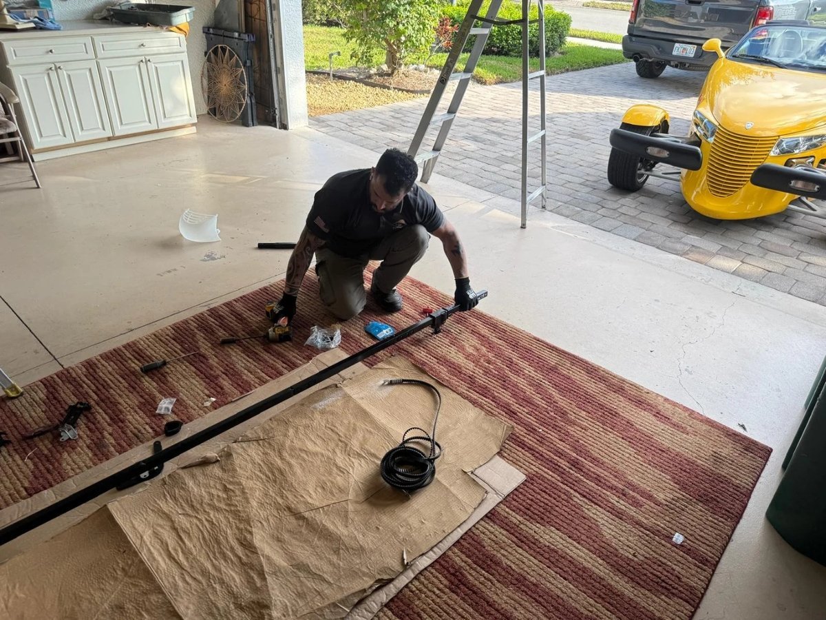 Technician assembling opener rail components on a protected garage floor